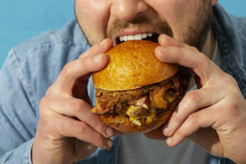 Eine Person hält einen saftigen Burger mit einem goldenen Brötchen und beabsichtigt, ihn zu essen.
