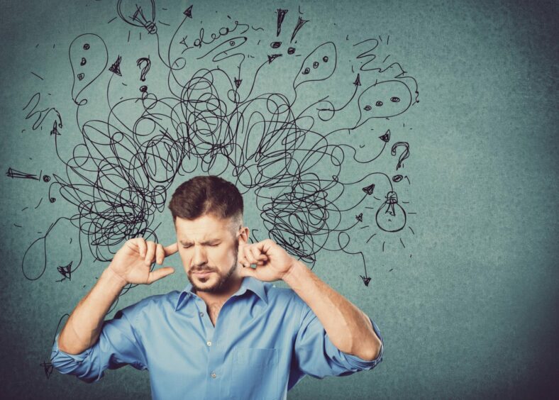 Ein Mann in einem blauen Hemd hält sich die Ohren zu, während verworrene Gedanken und Symbole über seinem Kopf schweben.